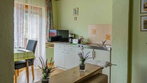 Una cocina compacta con comedor, televisor y cafetera.