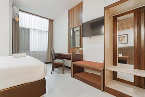 A hotel room with a bed, a desk, a chair, a TV, and a wardrobe. - Capital O 3932 Hotel Setrasari (Bandung)
