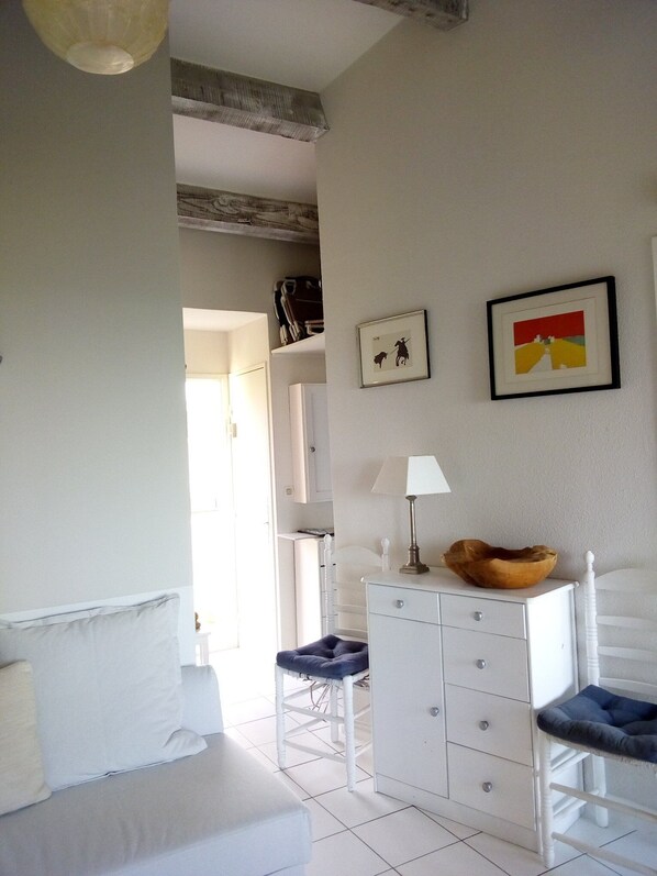 Ein Schlafzimmer mit einem Bett, einem Schminktisch, einem Sessel und zwei gerahmten Bildern an der Wand.