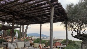 Zona d'estar a l'exterior amb moble de fusta i una pèrgola a la part superior.