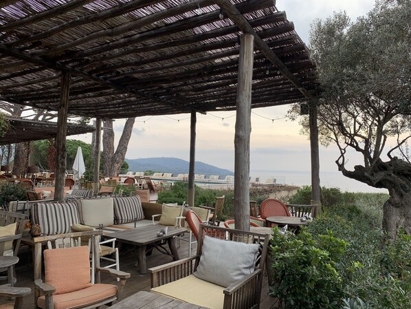 An outdoor seating area with wooden furniture and a pergola overhead.