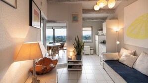 Una sala de estar moderna con un sofá, una mesita de centro y una lámpara. Se ve una vista de la ciudad desde la ventana.
