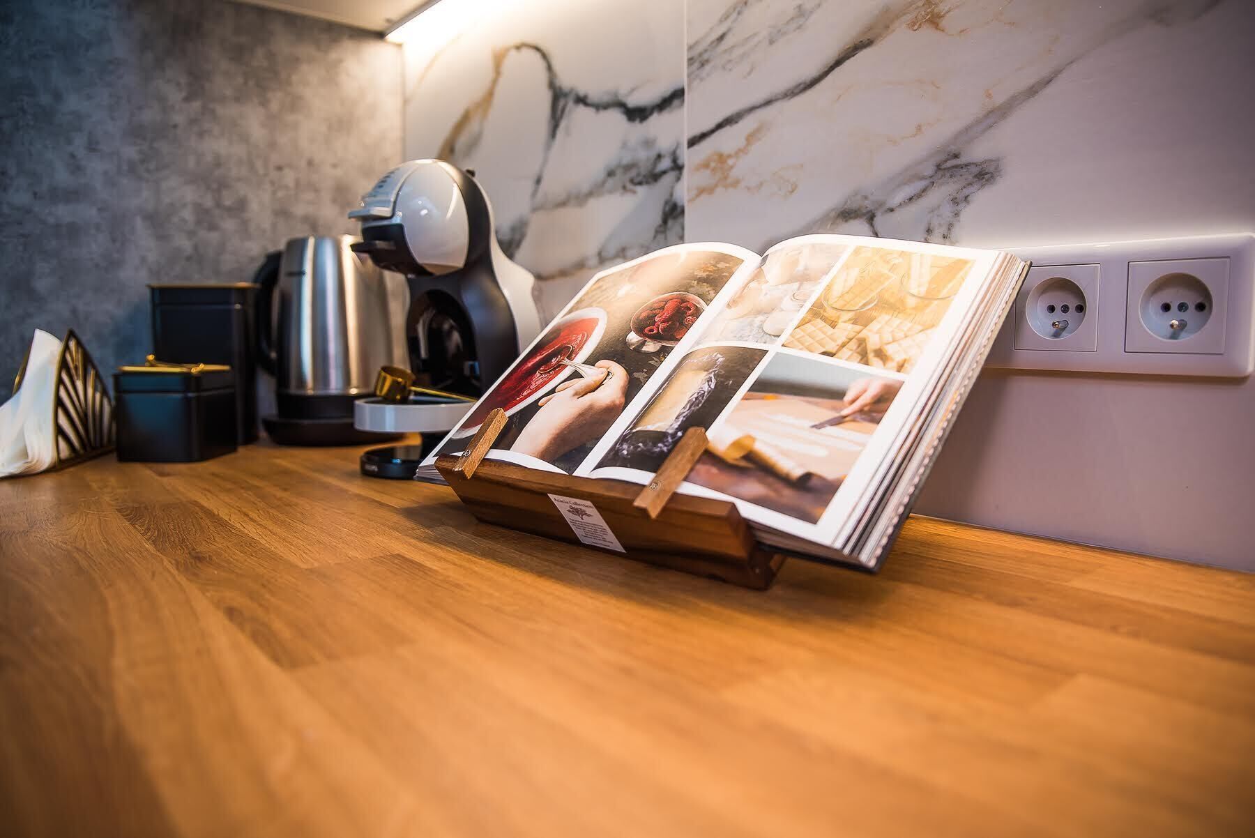A magazine on a wooden table with a marble wall and a coffee machine in the background.