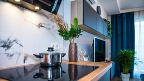 Een moderne keuken met een zwart aanrecht, een roestvrijstalen pan, een decoratieve vaas met groene planten, en een houten kast.