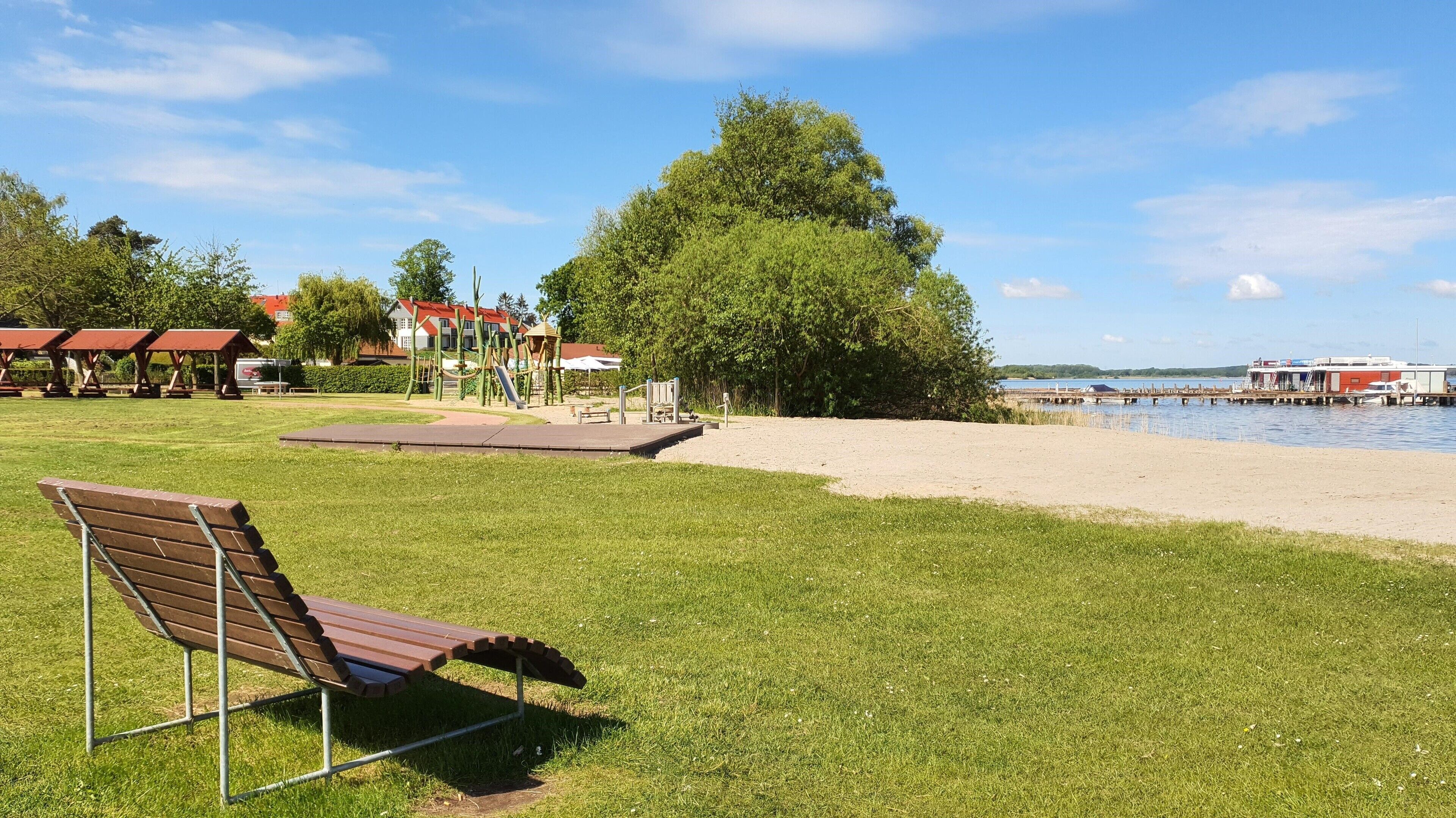 Un parc avec un banc, une aire de jeux et une vue sur un lac.