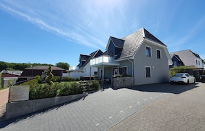 A modern two-story house with a tiled roof, a covered porch, and a paved driveway.