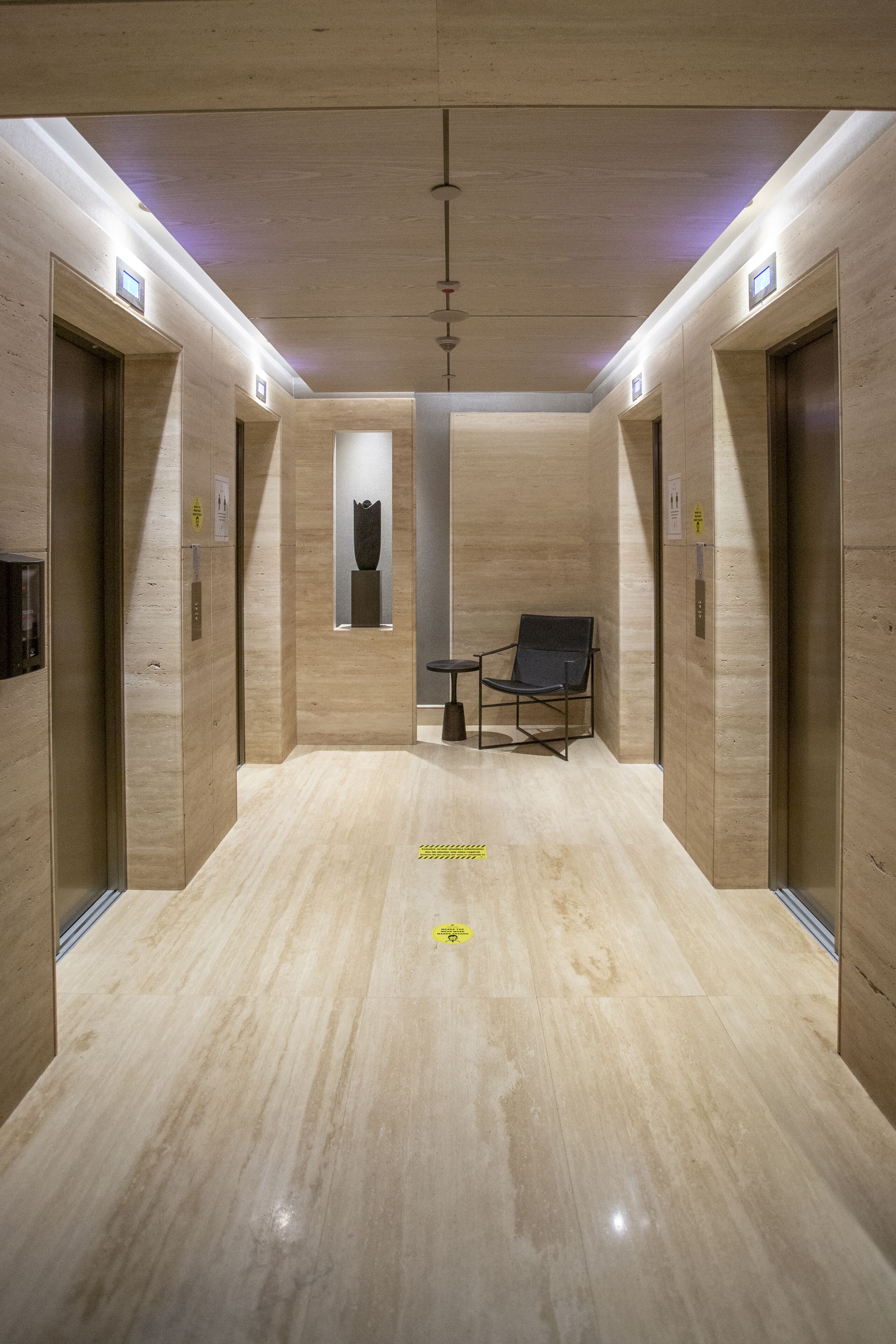 Un espacio moderno para ascensores, con paredes de madera y suelo pulido.