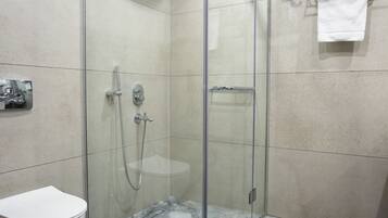 A modern bathroom with a glass-enclosed shower, a white toilet, and a marble floor.