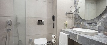 A modern bathroom with a marble sink, a glass shower enclosure, a toilet, and a vanity with a mirror.