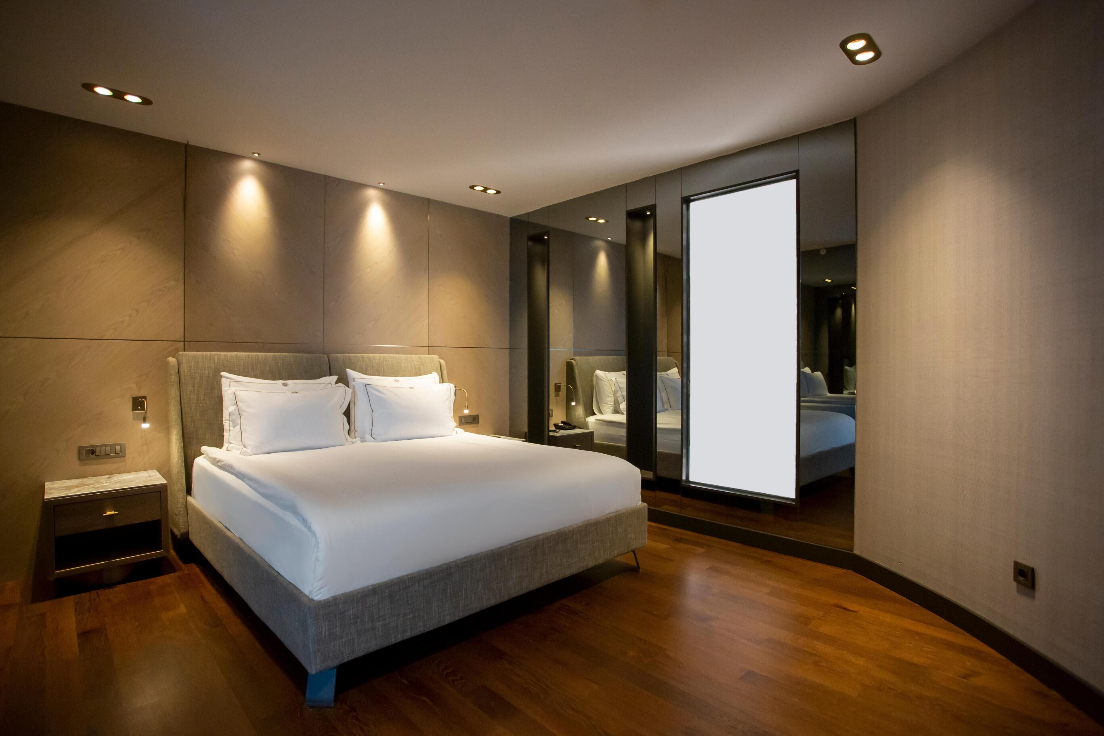 Une chambre moderne avec un grand lit, un plancher en bois et un grand miroir.