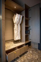 A modern bathroom with a marble vanity, wooden cabinetry, and a robe hanging on a rack.