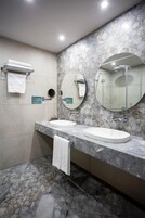 Un baño con dos lavamanos, un espejo grande y un perchero para toallas.
