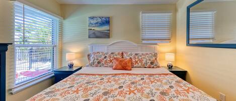 A bedroom with a bed, two nightstands, a headboard, a painting on the wall, and a window with blinds.