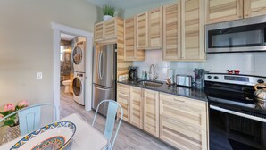 Una cocina moderna con armarios de madera, electrodomésticos de acero inoxidable y un comedor con mesa y sillas.