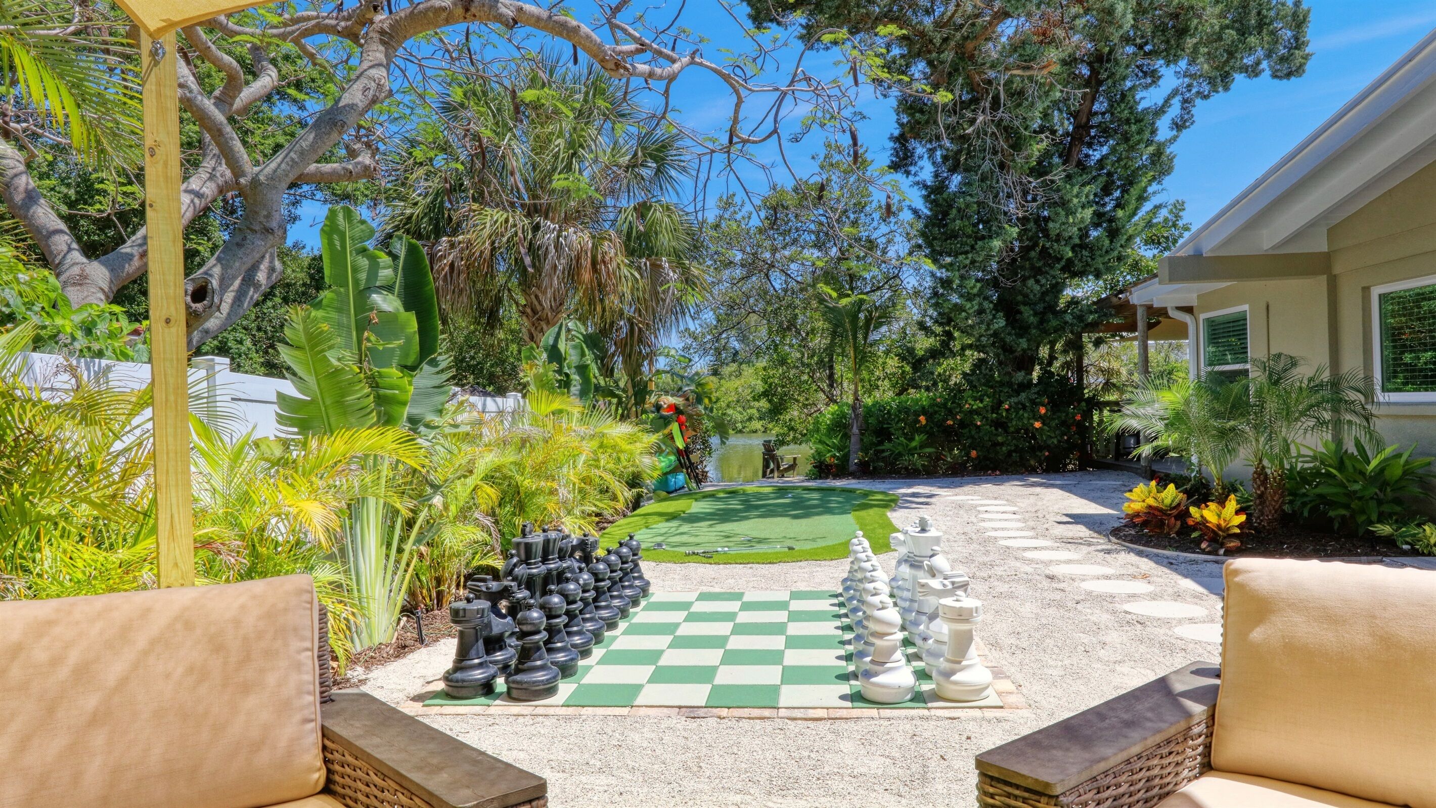 Ein Garten mit Schachbrettmuster auf der Terrasse, umgeben von üppiger Bepflanzung und Bäumen.