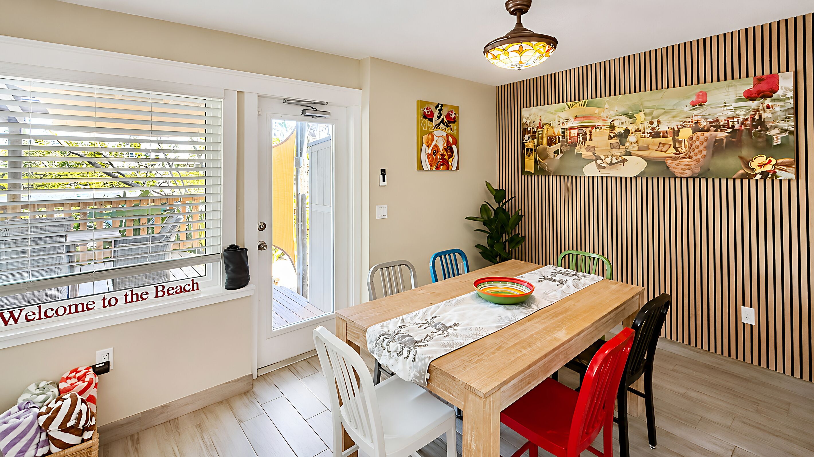 A dining area with a wooden table, chairs, a bowl, and a painting on the wall.