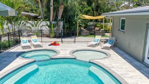 Une piscine divisée en deux zones distinctes, entourée de chaises longues et dotée d’un espace de repos abrité.