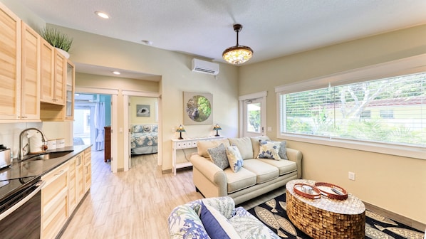 A modern kitchen with wooden cabinets, a built-in stove, and a sink. There is a dining area with a table and chairs, and a living room with a sofa and a coffee table. - Ground Floor Lakefront Resort, Private Dock, Heated Pool & Spa, Close to Beach (Anna Maria)