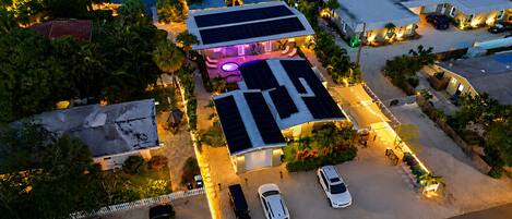 Vista aérea de una zona residencial con paneles solares, piscina y varios coches estacionados.