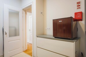 A hallway with a white door, a wooden cabinet, and a red fire safety sign on the wall. - Basil Red Apartment, AC, Wifi !new! (Lisboa)