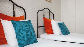 A double bed with a white mattress and multiple pillows in various colors.