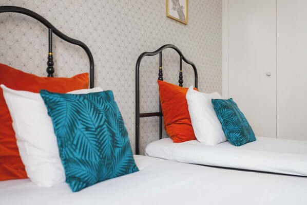 Un lit double avec un matelas blanc et plusieurs oreillers de différentes couleurs.