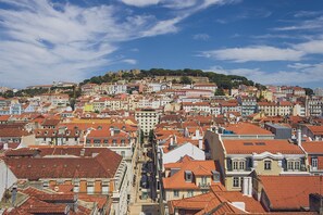 A densely packed urban area with a variety of building styles and a prominent hill with a castle-like structure in the background.