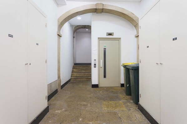A hallway with white walls, a stone floor, and an arched doorway leading to a staircase. - Basil Red Apartment, AC, Wifi !new! (Lisboa)