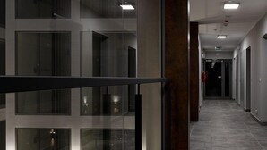 A modern hallway with glass panels and a metal railing, leading to an elevator. - EASY RENT Apartaments - SMART 318 (Lublin)