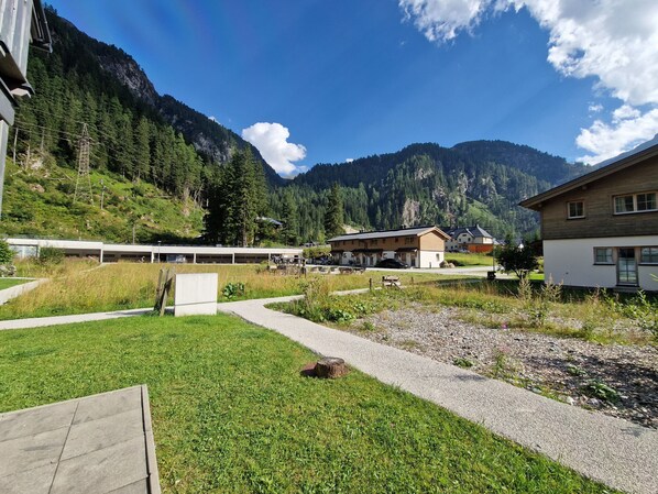 A hotel with a mountain backdrop, a parking area, and a grassy courtyard. - Lodge Weißsee 160 in the Tauern village of Enzingerboden (Uttendorf)