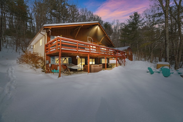 A cabin with a wooden exterior, a balcony, and a hot tub.