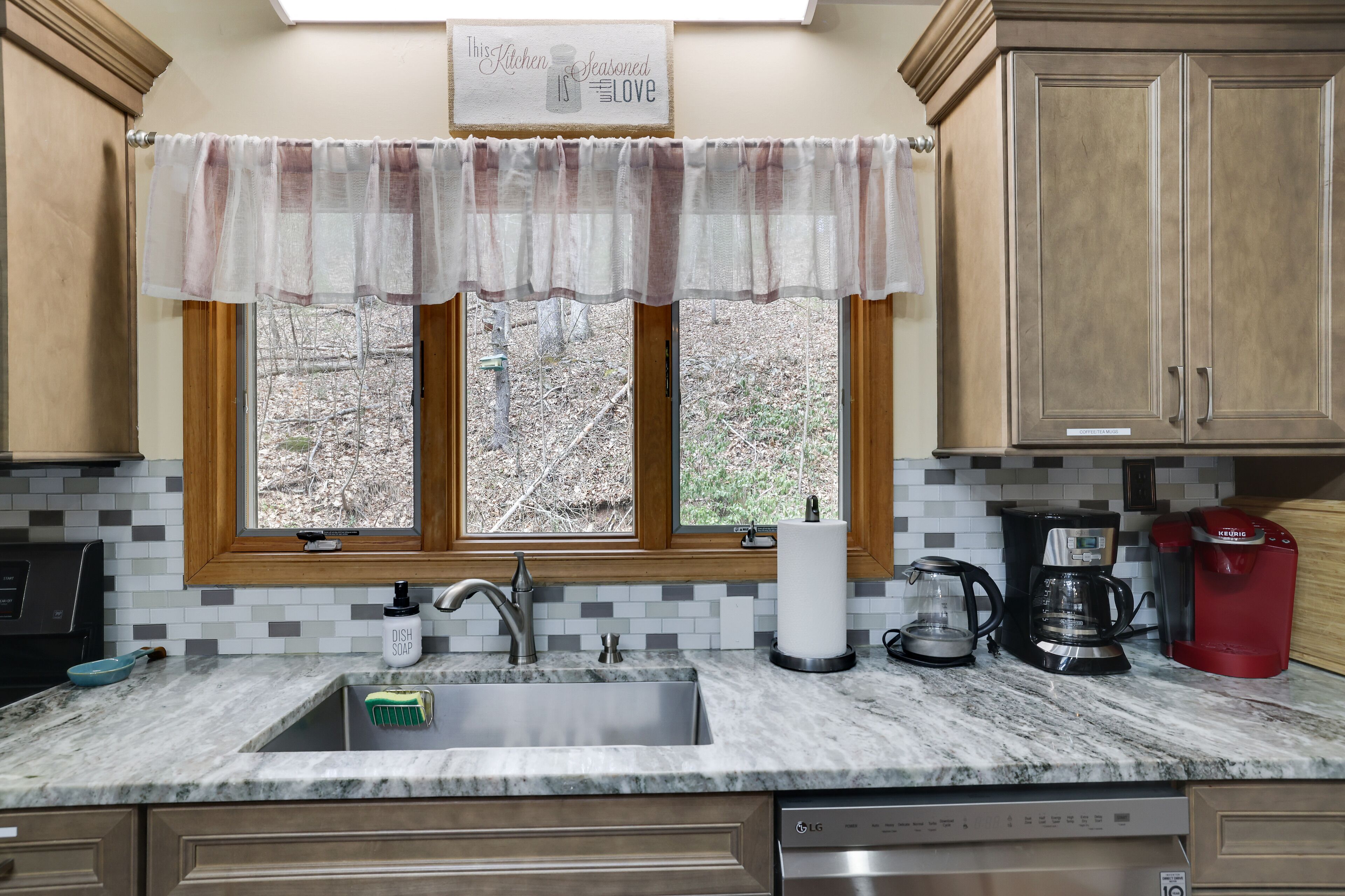 A kitchen with a double sink, a coffee maker, and a dish soap bottle.