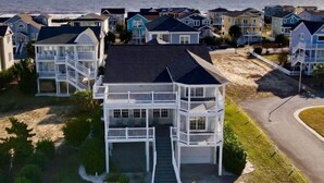 Zona residencial costeira com casas de vários andares, com varandas e uma praia ao fundo.