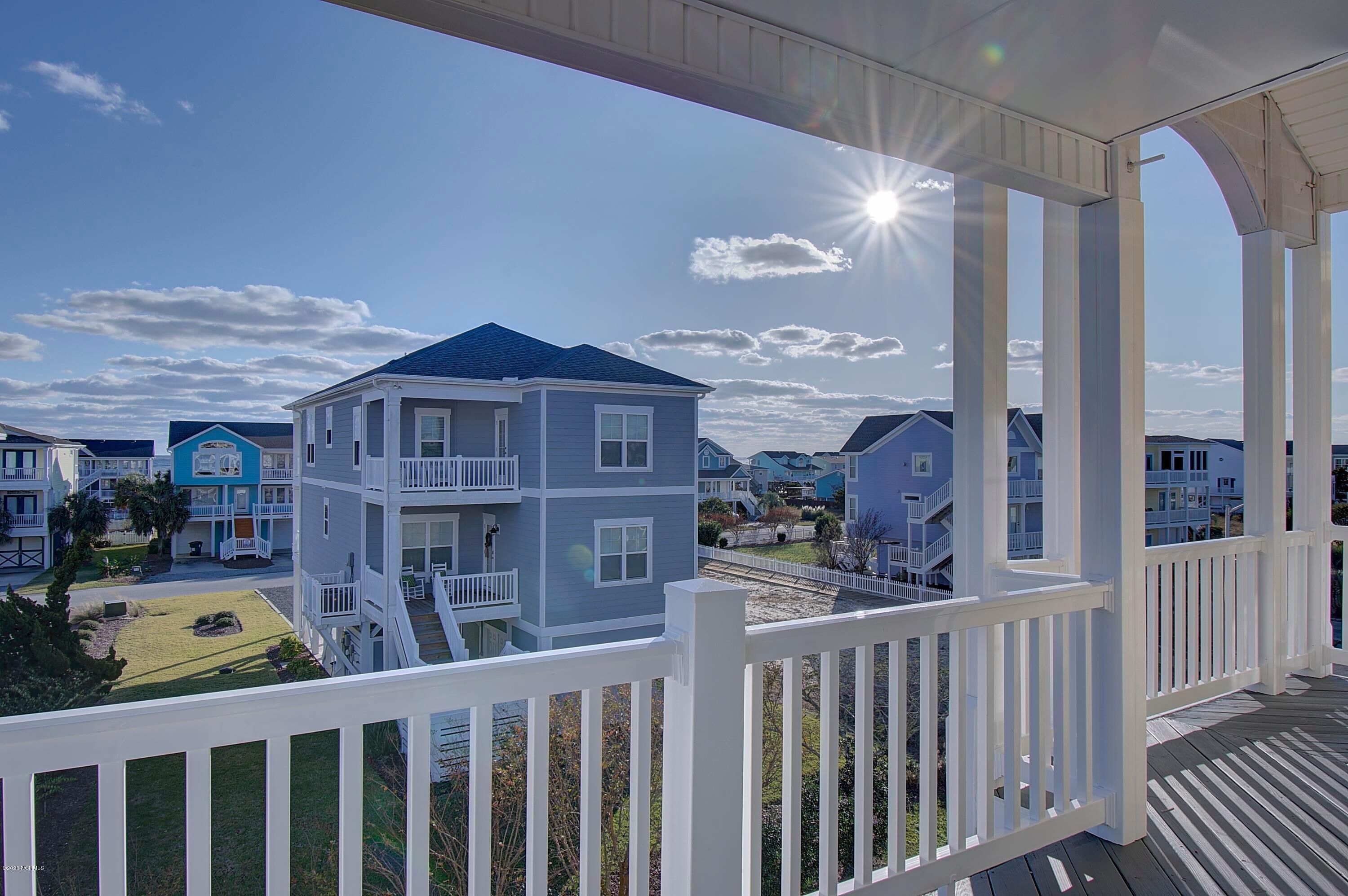 A multi-story house with a balcony, a clear sky, and the sun shining.