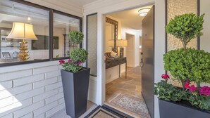 A modern entryway with a white brick wall, a large potted plant, a mirror, and a doorway leading to a bathroom. - 3819 Casa Carmela - Private Home in Carmel (Carmel)