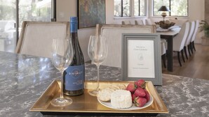 A dining table with a bottle of wine, glasses, a tray with cheese and strawberries, and a framed welcome sign. - 3819 Casa Carmela - Private Home in Carmel (Carmel)