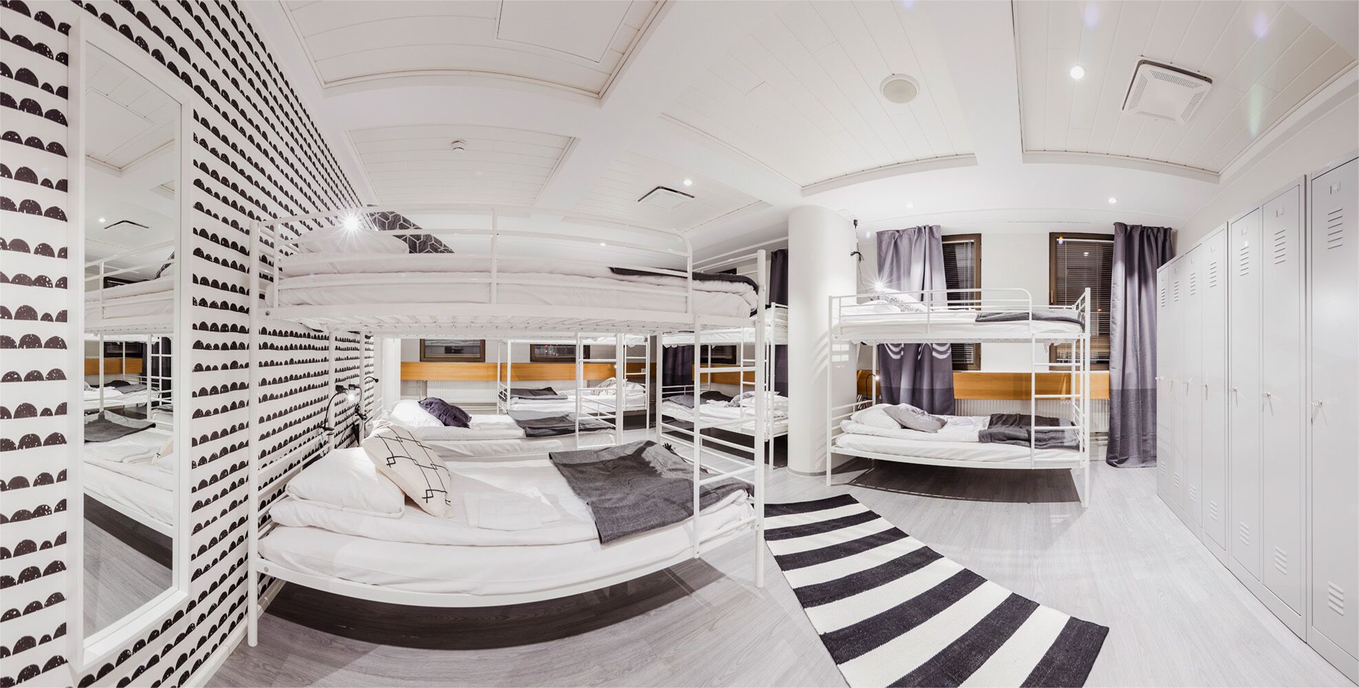 A bunk room with multiple beds, a shoe display wall, and a striped rug.