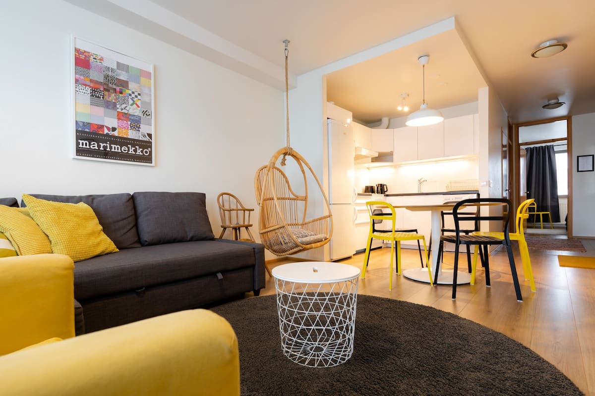 Un salon moderne avec un canapé, des fauteuils, un fauteuil suspendu et une petite table ronde.