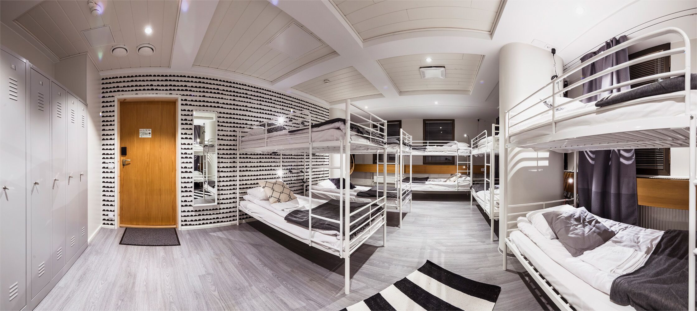 A dormitory-style room with bunk beds, a shoe rack, and lockers.