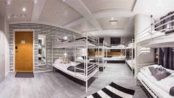 A dormitory-style room with bunk beds, a shoe rack, and lockers.