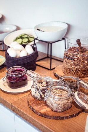 A breakfast buffet with various food items including eggs, granola, and jars of preserves. - Hostel Café Koti (Rovaniemi)