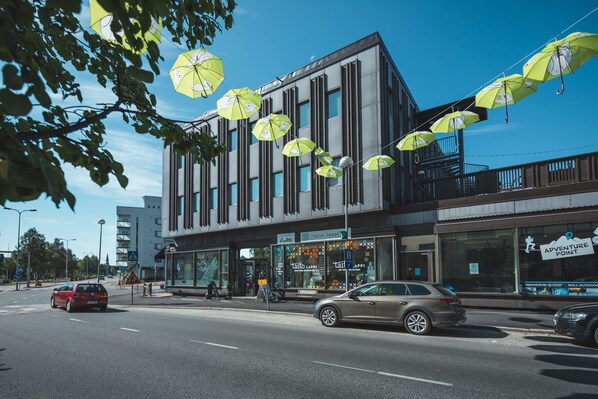 A modern building with a glass facade and a storefront with a sign that reads "Adventure Point". - Hostel Café Koti (Rovaniemi)