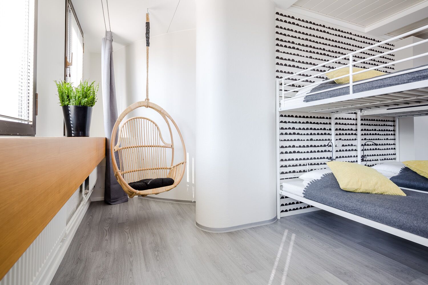 Una habitación moderna con una silla colgante, literas y un zapatero de pared.