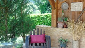 Un espace extérieur aménagé dans un style rustique, avec un banc en bois, un mur en pierre et des plantes en pot.