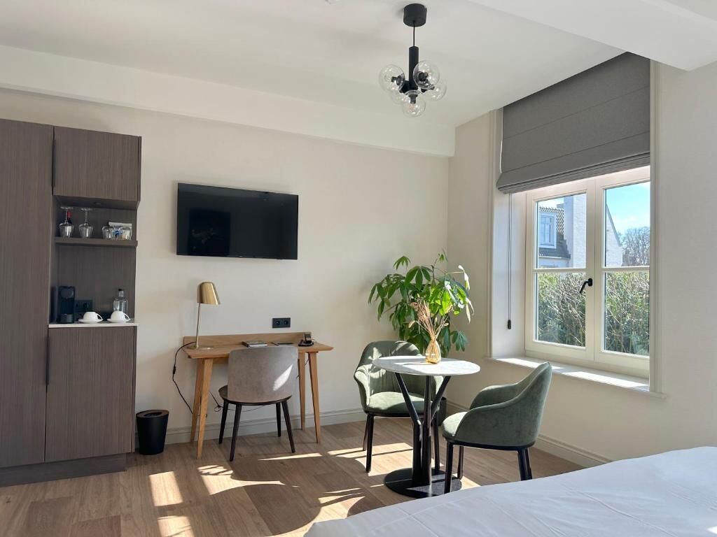 Une chambre moderne avec un lit, un bureau et une chaise. Il y a un téléviseur accroché au mur et une fenêtre donnant sur un beau paysage.