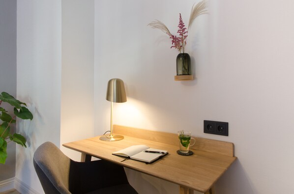 A wooden desk with a lamp, a notebook, and a glass of water. - Hotel Flora Batava (Nieuwersluis)