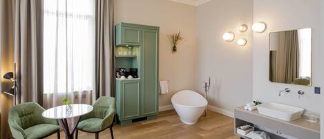 Un baño moderno con una bañera independiente, un tocador con un espejo grande y un armario verde con estantes.