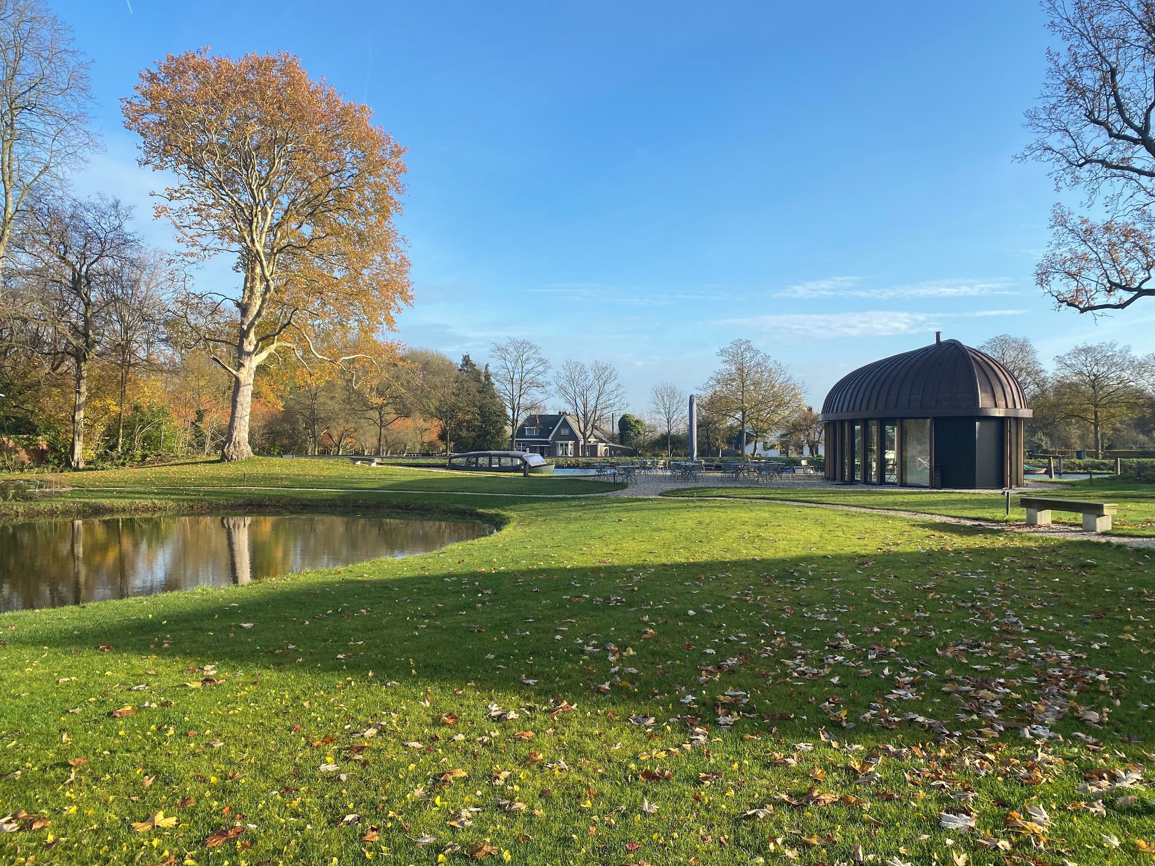 A park with a pond, a gazebo, and a house in the background.