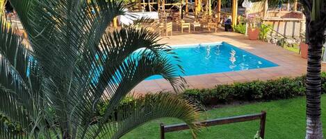 A swimming pool surrounded by lush greenery and a wooden swing.