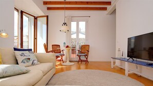 A living room with a sofa, chairs, a TV, and a table.